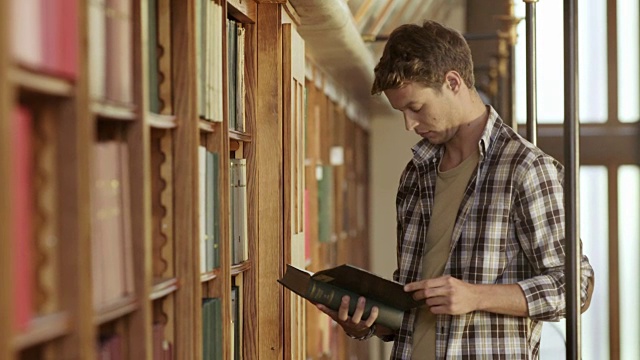 一个年轻人在图书馆里翻看一本书视频素材