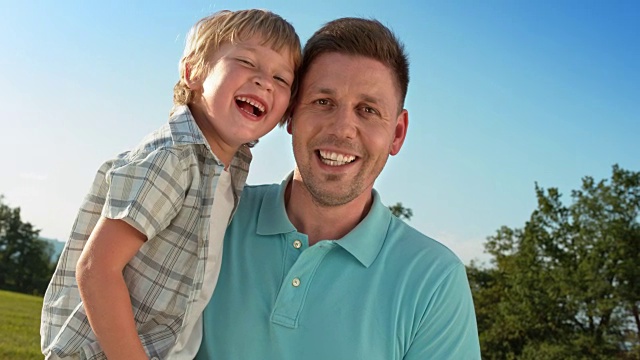 SLO MO的肖像，一个父亲抱着他的儿子，微笑着对着相机视频素材