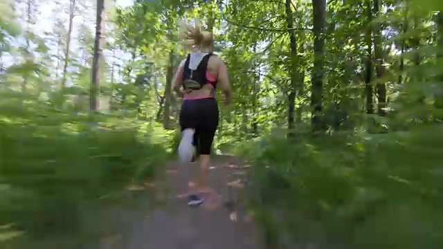 TS女跑步者沿着森林小径奔跑视频素材