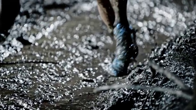 SLO MO DS女性的腿在晚上跑过一个泥泞的水坑视频下载