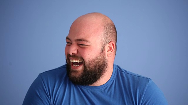 蓝色背景下大笑的成年男子的面部表情视频素材