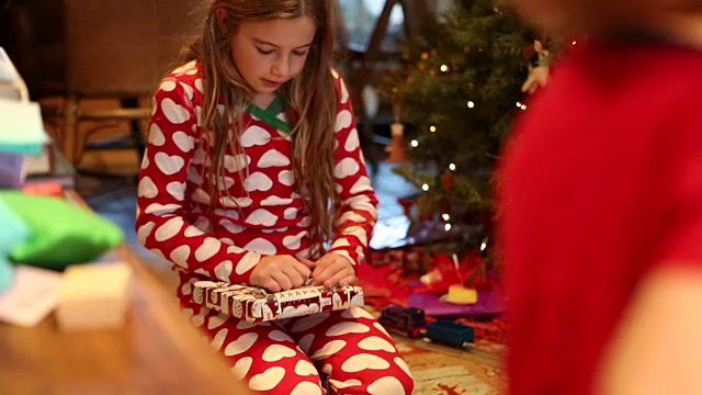 9岁的女孩在圣诞节早上打开礼物视频素材