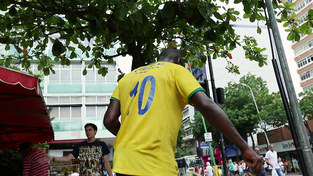 这张照片拍摄于巴西里约热内卢的一个街角，一个有色人种拿着巴西三叉戟玩自由式足球视频下载