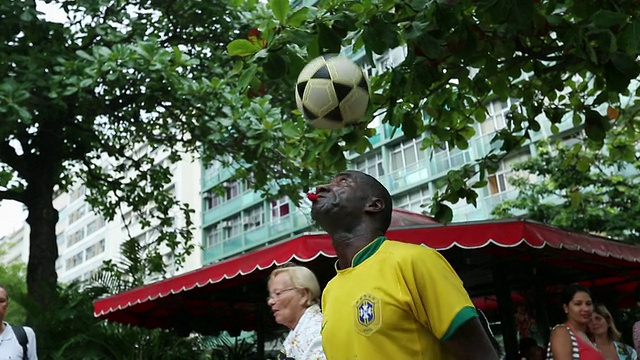 这张照片拍摄的是一个有色人种和巴西人在街角玩自由式足球视频下载