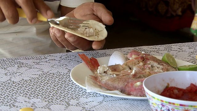 墨西哥金塔纳罗奥，图伦，一名男子正在将煮熟的朱红鲷鱼肉和莎莎酱放入软的墨西哥煎玉米卷中视频下载