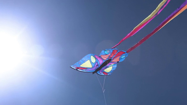 五颜六色的风筝在蓝天和太阳耀斑中飞翔视频下载