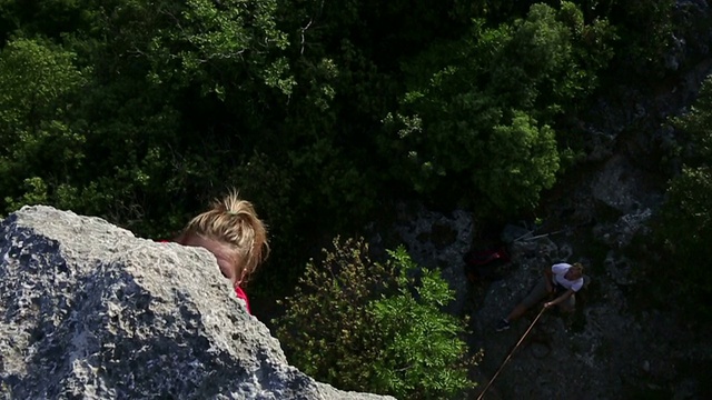 年轻女子攀登陡峭的岩壁之上的保护者视频素材