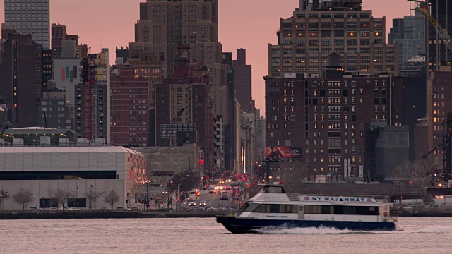 一股粉红色的光芒从曼哈顿的天际线升起，一艘渡轮横过框架视频素材