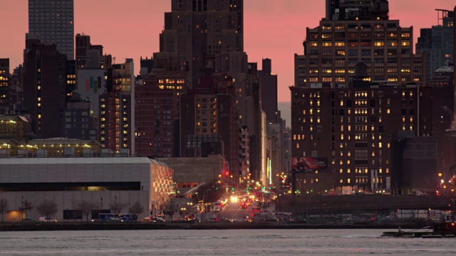 一股粉红色的光芒从曼哈顿的天际线升起，一艘渡轮横过框架视频素材