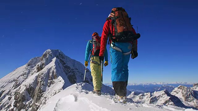 在阳光下，登山队员们正在穿越积雪的山脊视频下载