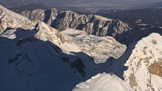 登山队员们在阳光明媚的山脉中行走视频素材