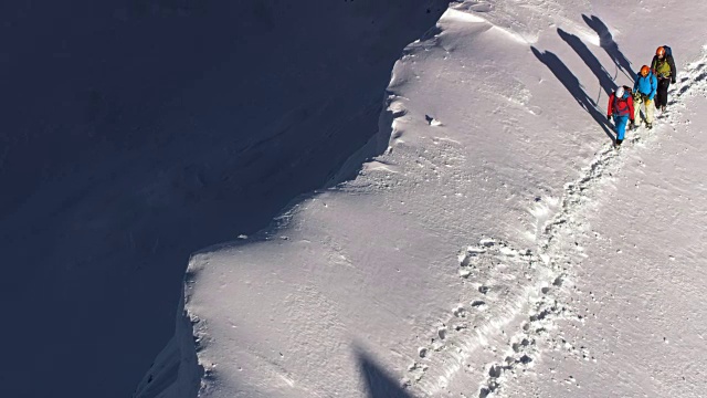 潘:三个男人正沿着积雪的山脊向上走视频素材
