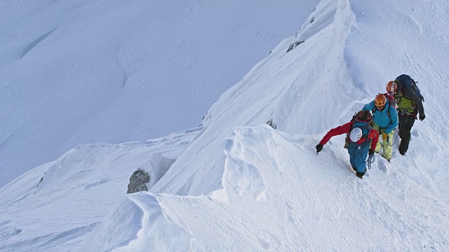 三个登山运动员正在爬上白雪覆盖的山脊视频素材