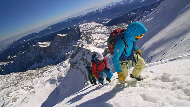 潘用绳子把在阳光下攀登雪山的登山队员捆起来视频素材