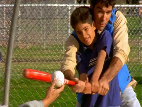 西班牙裔父亲帮助儿子练习由另一个男人拿着的击球视频素材