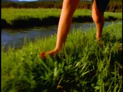 慢镜头近距离跟踪拍摄的男孩光腿跑在草地溪/火花草地，喀斯喀特山脉，俄勒冈州视频下载