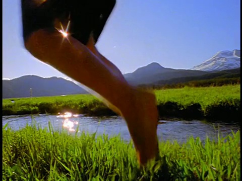 慢镜头男孩跳过青蛙在小溪/火花草地，喀斯喀特山脉，俄勒冈州视频下载