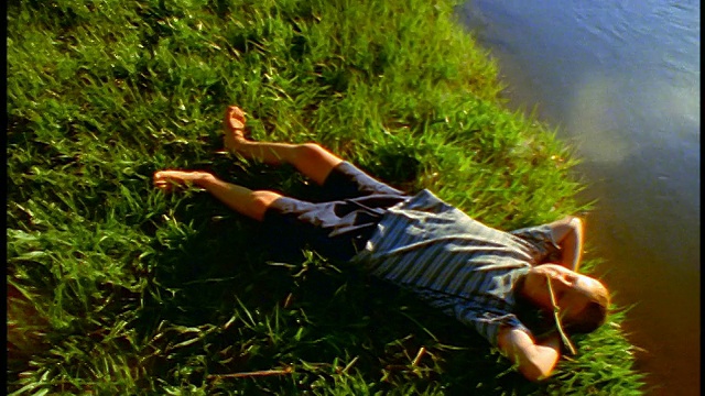 在俄勒冈州喀斯喀特山脉，男孩躺在溪流/斯帕克斯草地的草地上视频下载