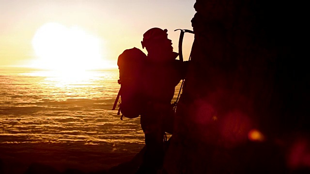 图为登山运动员在美丽的日落中爬山的剪影视频素材