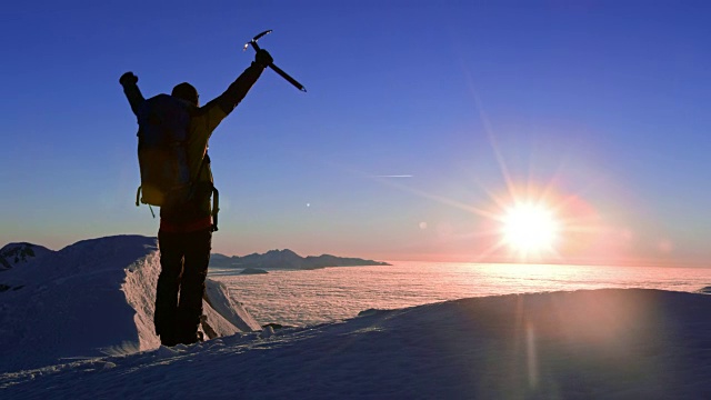 日落时分，一个登山运动员在山顶举起双手视频素材