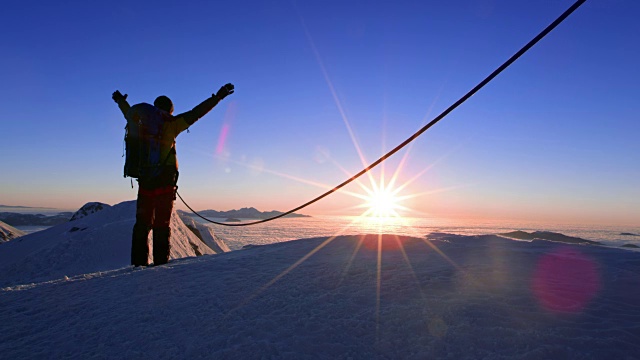 日落时分，绳索登山队成员在山顶举起双手视频素材