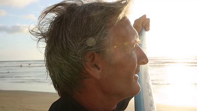 成熟的冲浪者的肖像，在日出的海滩上视频下载