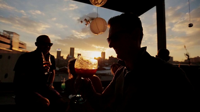 手持拍摄的日落，一个人喝鸡尾酒的剪影视频下载