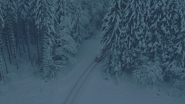 空中汽车行驶在被雪封的森林道路上视频下载