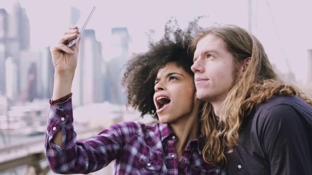 一对情侣在布鲁克林桥上用智能手机自拍视频素材