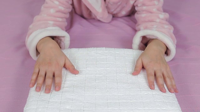 女人在床上抚平一条干净的白毛巾。视频素材