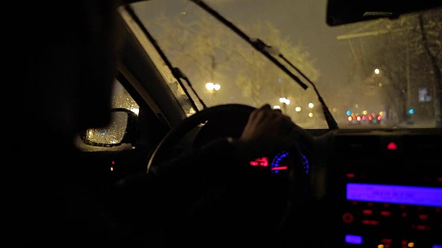 一个年轻人在一个下雪的夜晚开车。视频素材