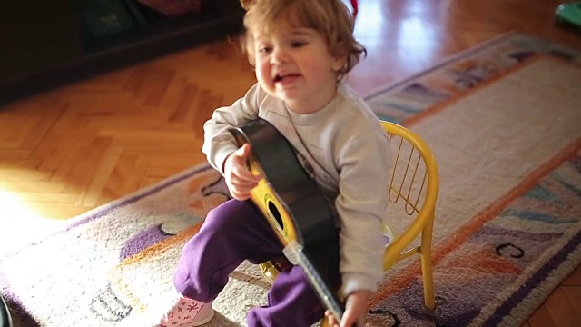 可爱的小女孩一边弹玩具吉他一边唱歌视频下载