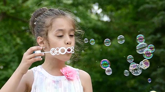 孩子在公园里吹肥皂泡的慢动作视频素材