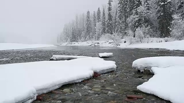 广角拍摄的河流在山上与积雪覆盖的树木和河岸覆盖在大雪暴风雪。视频素材