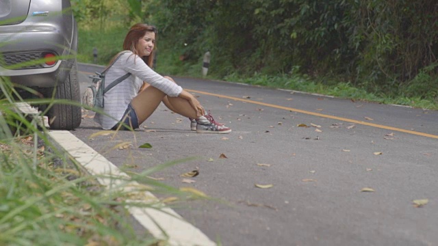 一个伤心的漂亮女孩在车祸后坐在马路上视频素材