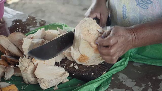 尼加拉瓜一名妇女用一把大刀削椰子。在这个4K视频中，我们可以看到一个来自中美洲的原住民的手在Masaya市场上切这种异国水果的皮肤。视频下载