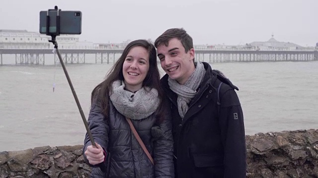 一对年轻夫妇在冬天的海滩上自拍。视频素材