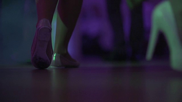 在夜总会或迪斯科舞厅的舞池上跳舞的女人和男人的脚的特写。围观穿着高跟鞋的美腿女人跳舞。视频素材