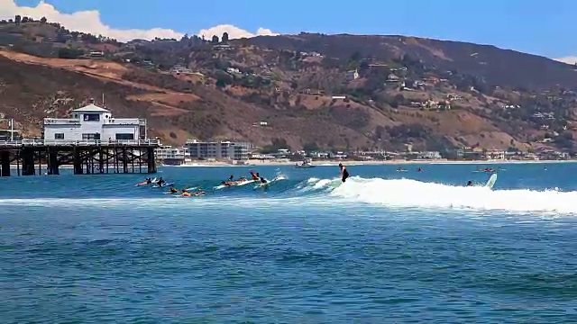冲浪者在马里布海滩附近的码头享受高潮，太平洋，加利福尼亚视频素材