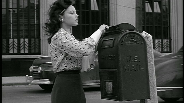 1948年妇女在城市街道/工业的邮箱里邮寄信件视频素材