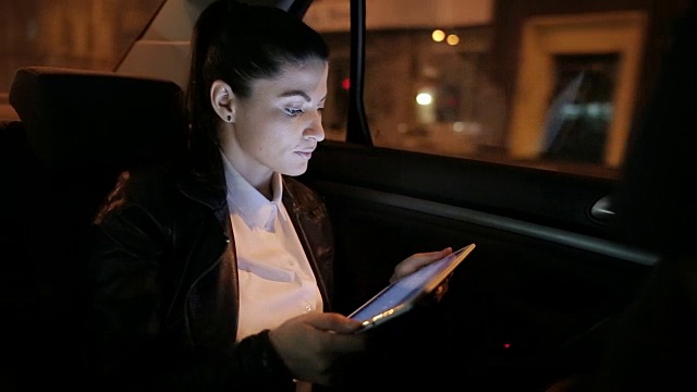 一个年轻漂亮的女人在车里用平板电脑。视频素材