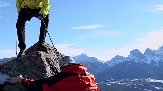 年轻的导游扶着朋友爬上陡峭的山脊视频下载