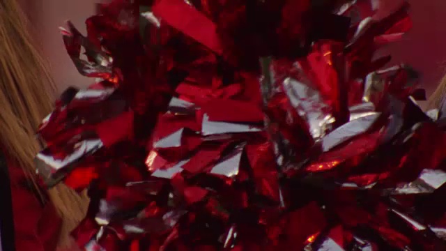 慢镜头极端特写的啦啦队长在一场大学橄榄球比赛的球。视频下载