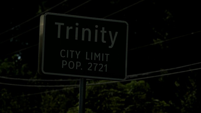 高速公路小镇的夜间标牌上写着:“Trinity City Limit pop”。2721年视频素材