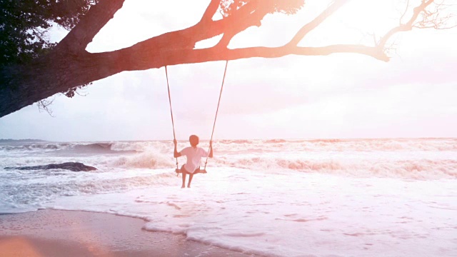 慢镜头，少年在海边荡秋千。视频素材