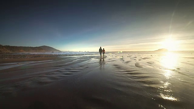 年轻夫妇徒步在太平洋海滩日落视频素材