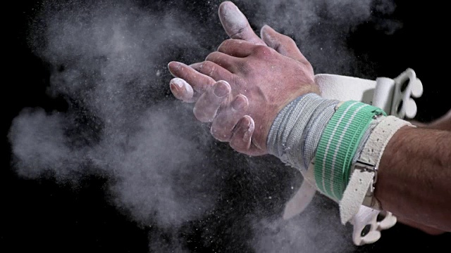 SLO MO男子体操运动员戴着握拍他的手灰尘与粉笔视频下载