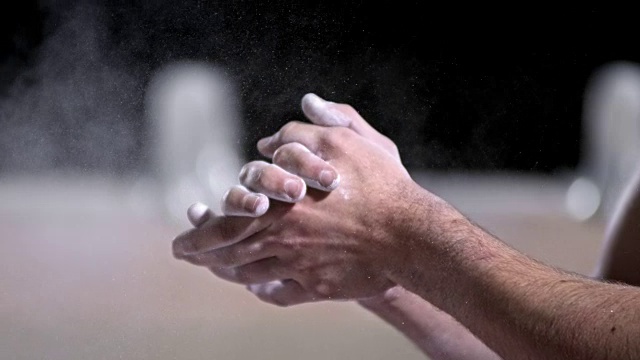 SLO MO男子体操运动员通过拍手除去多余的粉笔视频素材