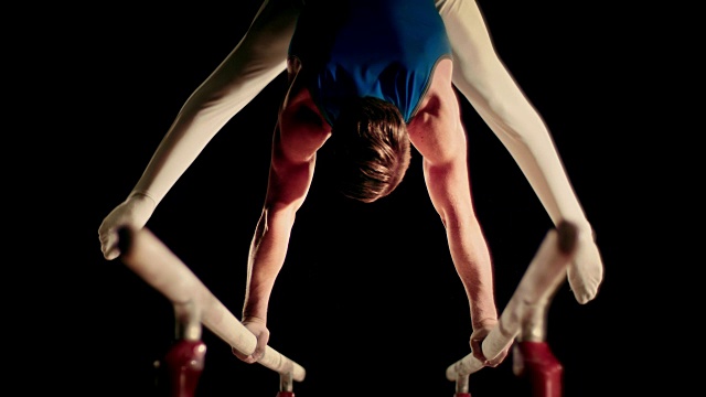 SLO MO男子体操运动员在双杠上做他的常规动作视频下载