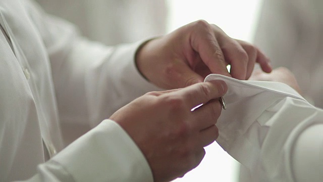 男性的手打扮新郎的特写镜头。男人正在调整袖扣。视频下载